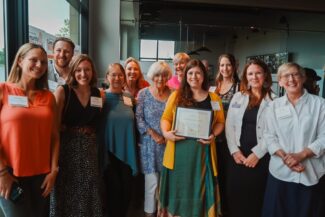 Cordia CEO, alongside staff and friends, holds up award