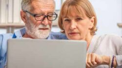 Couple researching senior living communities on laptop computer.