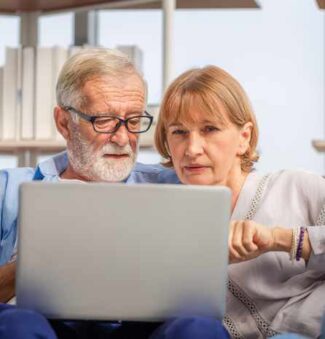 Couple researching senior living communities on laptop computer.